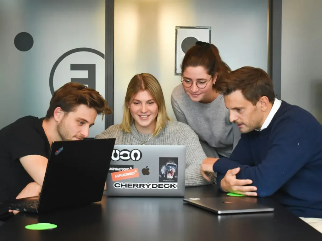 Designers collaborating around a laptop in a modern studio